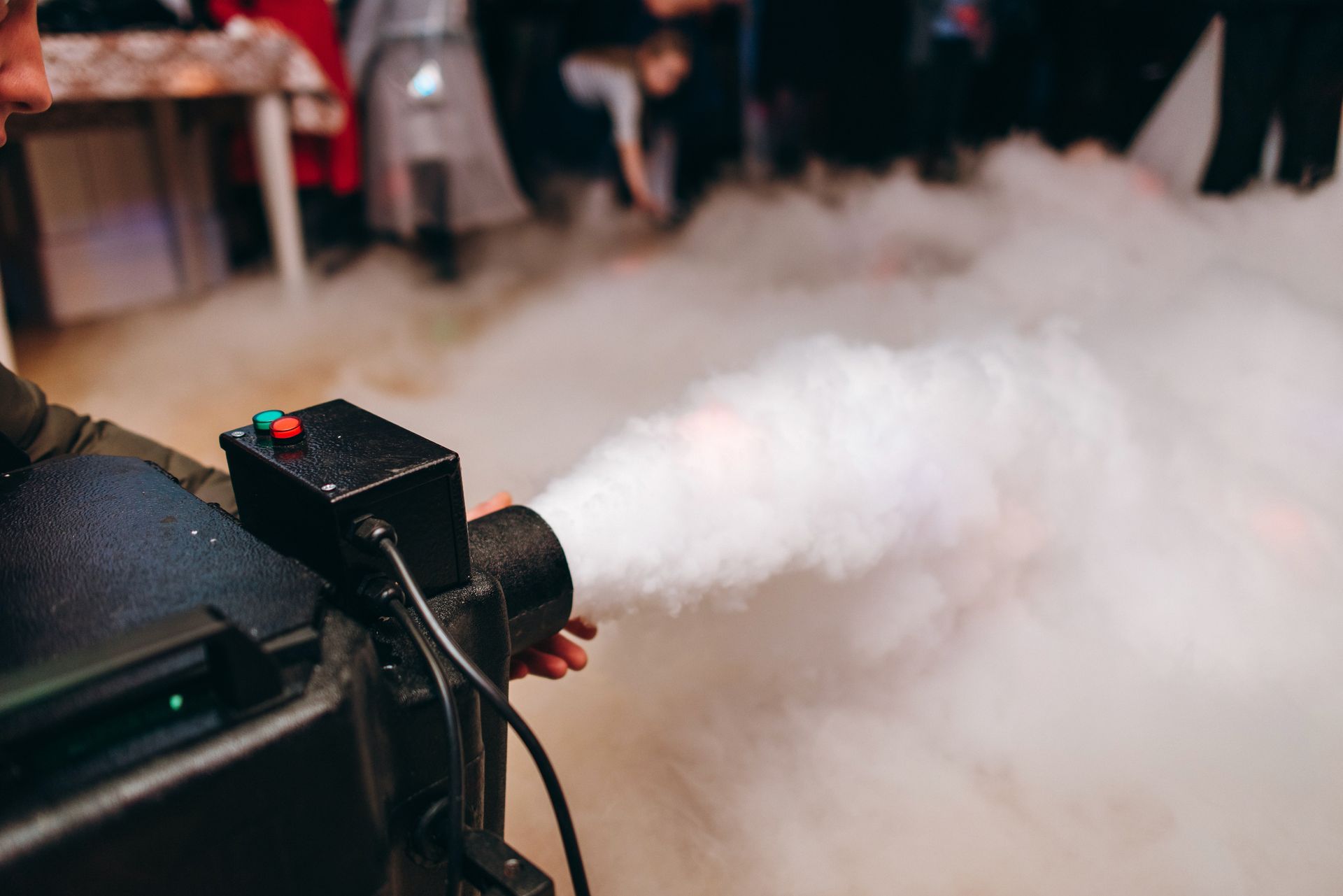 A person is using a machine to make smoke at a party.