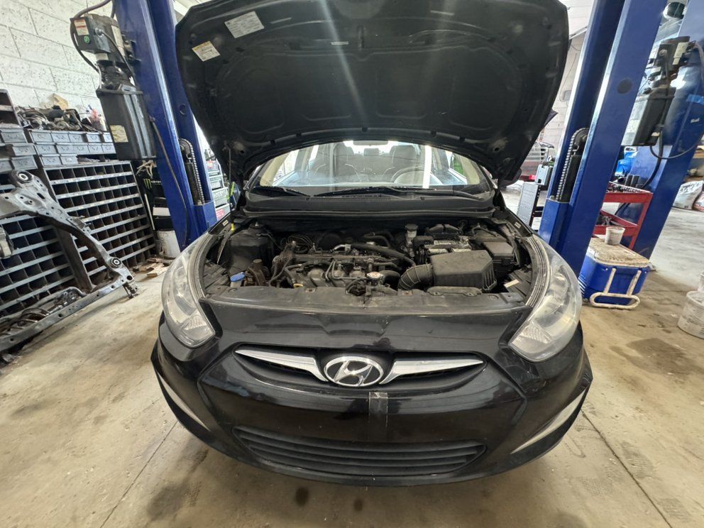 Black Hyundai car with open hood in a garage.