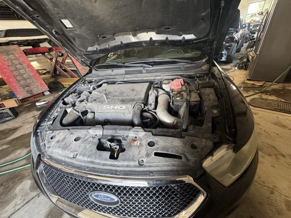 Ford car engine bay open for repair in a workshop.