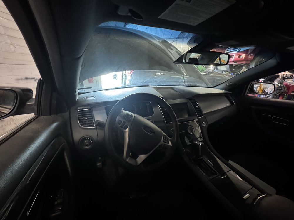 Interior of a dark-colored car with the hood open, revealing the dashboard, steering wheel, and windshield.
