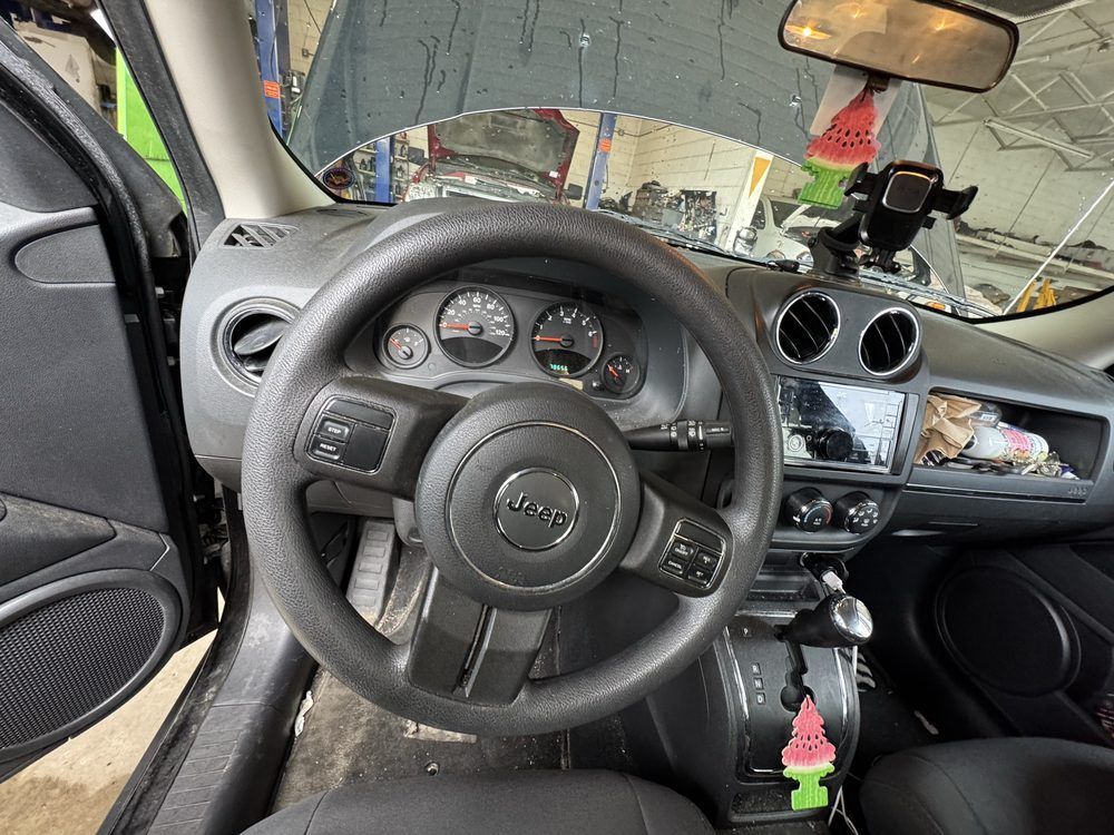 Dashboard of a Jeep vehicle with steering wheel, gauges, and radio display. The hood is open.
