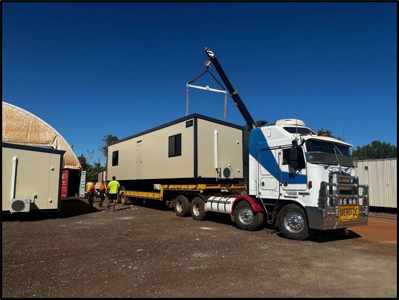 A semi truck is carrying a container with a crane attached to it