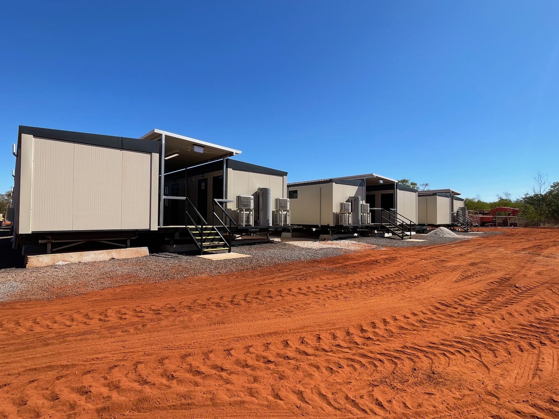 A row of trailers are parked in a dirt field.