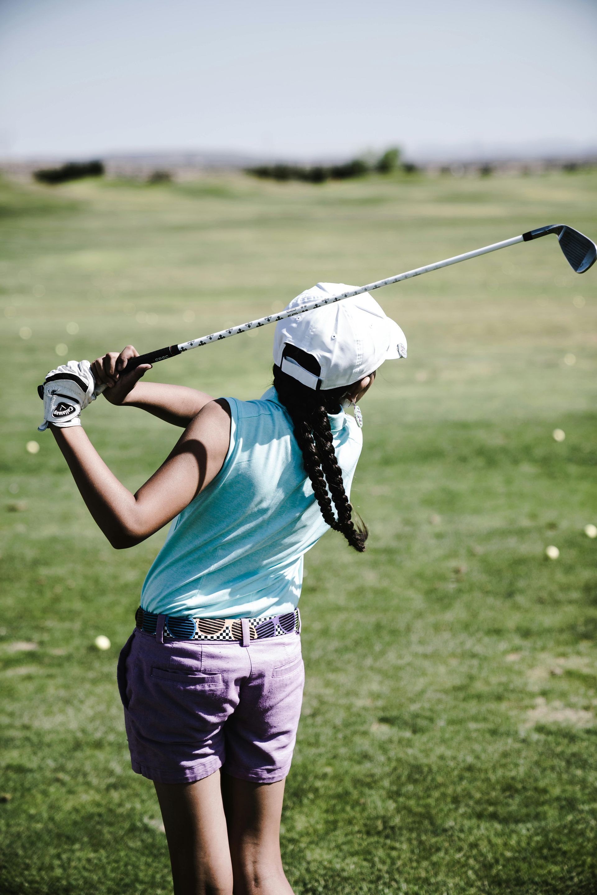 A woman is swinging a golf club on a golf course.