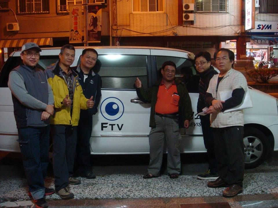 夜晚的街道上,一群男子站在一輛白色FTV貨車旁。其中一名男子指著路邊。