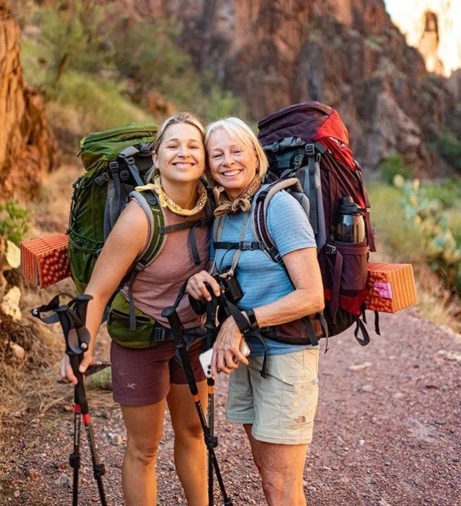 Mother and Daughter with backpacks and hiking poles are posing for a picture