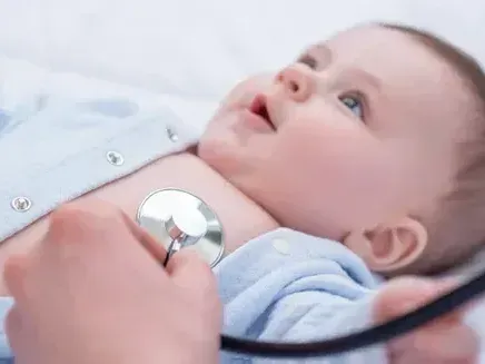 A baby is being examined by a doctor with a stethoscope.