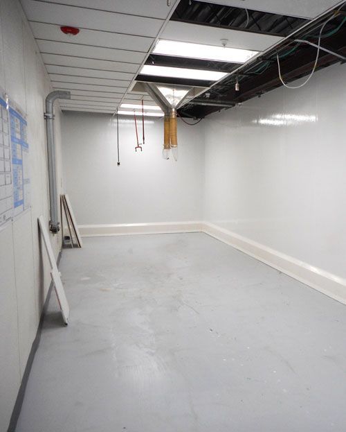 A large empty room with white walls and a gray floor.