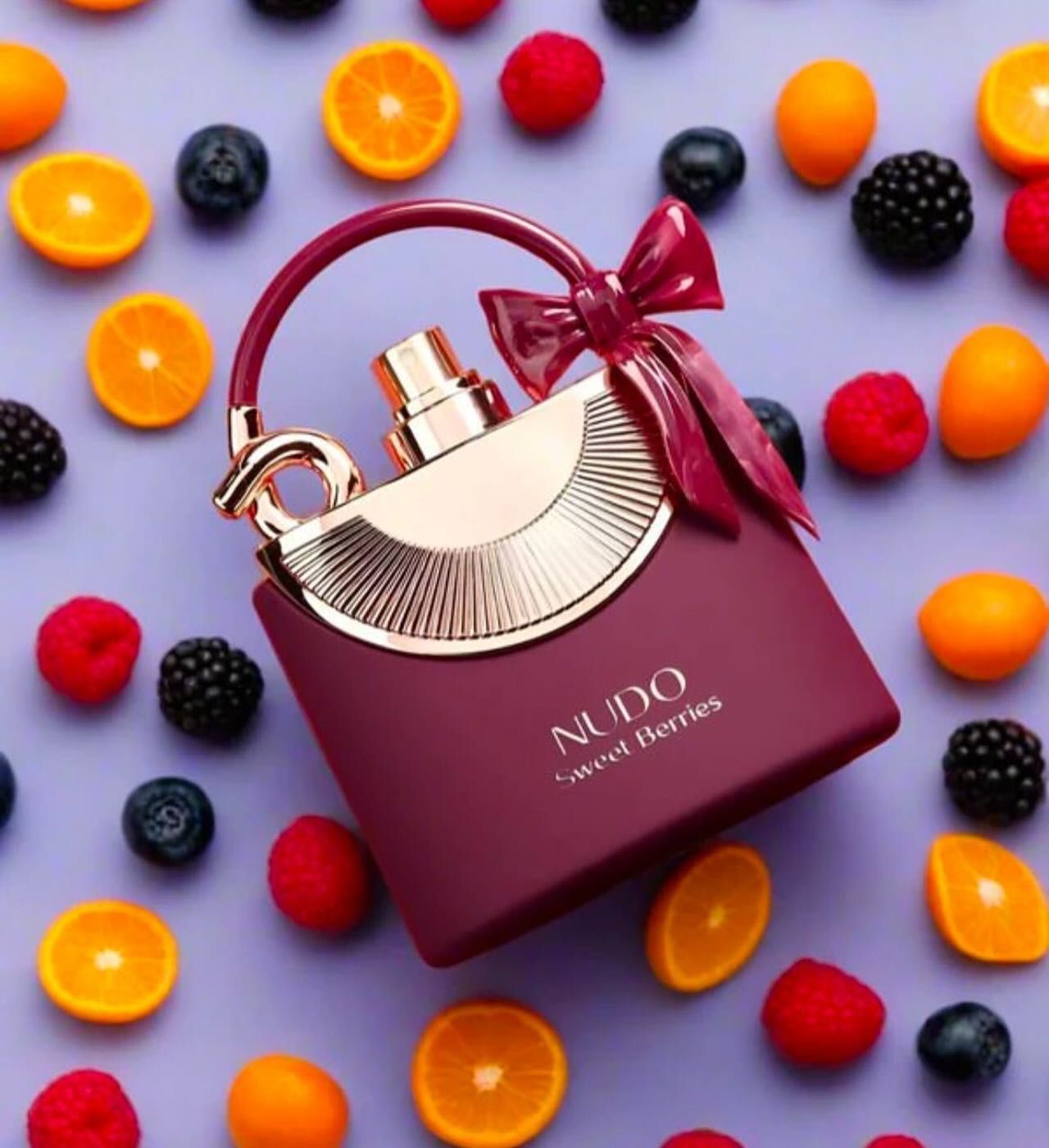 Frasco de perfume morado con lazo y asa, pinceles de maquillaje, pendientes y anillos dorados sobre fondo naranja.