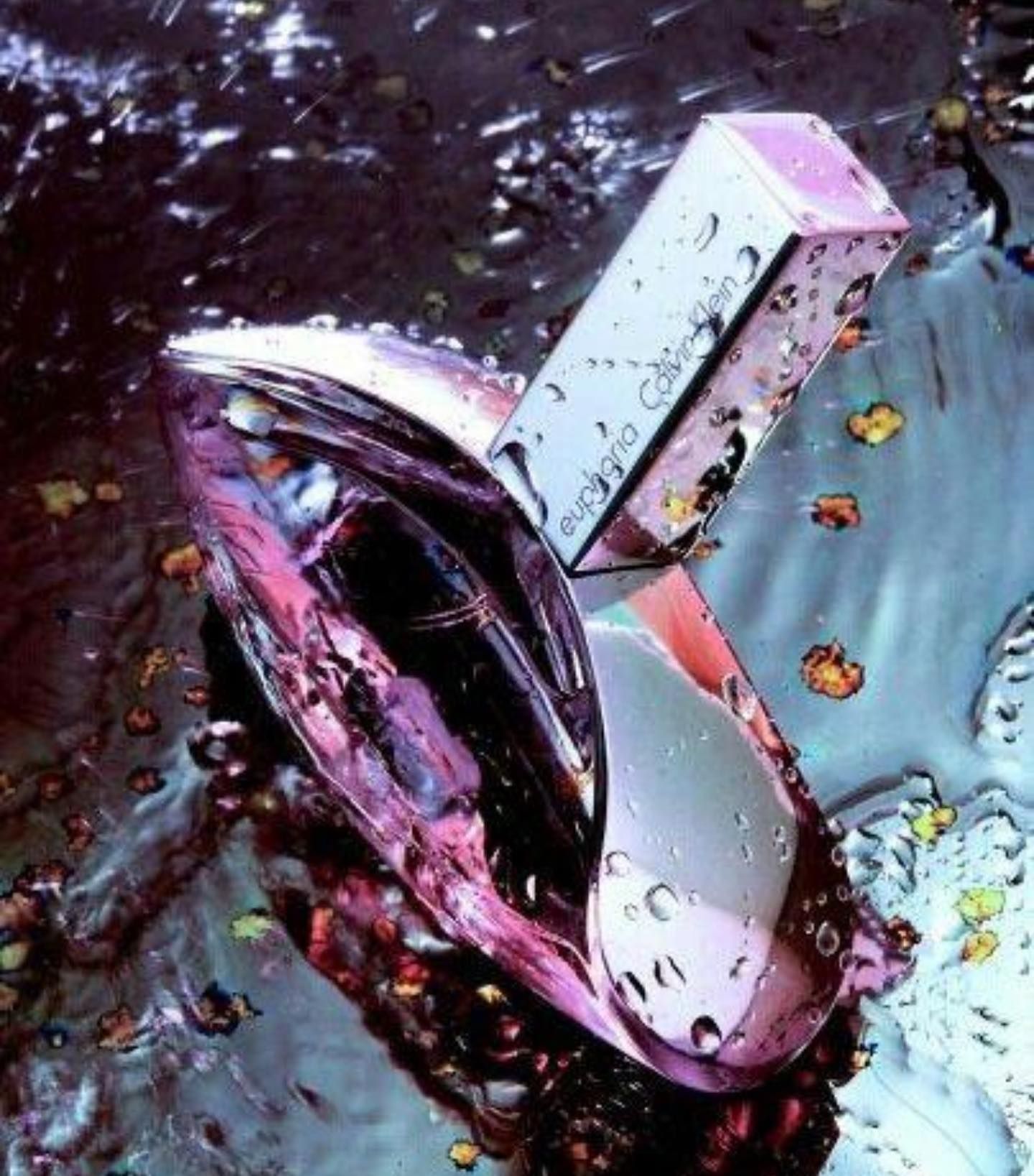 Frasco de perfume Calvin Klein Euphoria con flor de orquídea sobre fondo rosa.