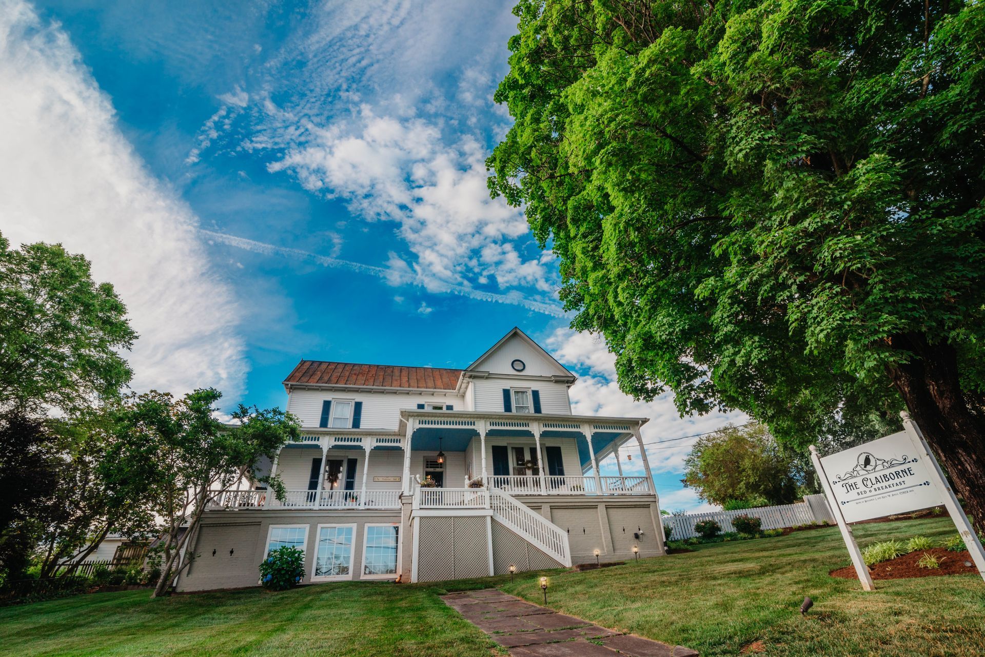 A large white house is sitting on top of a lush green hill.