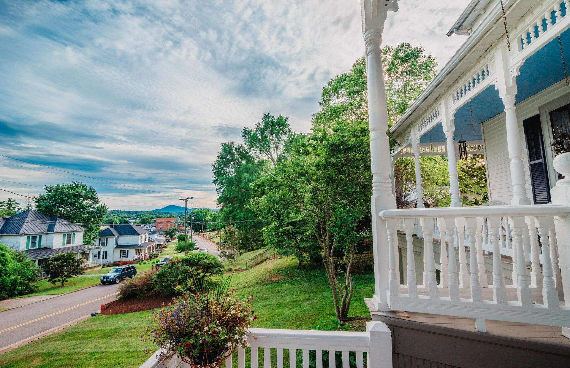 A porch of a house with a view of a street and trees.