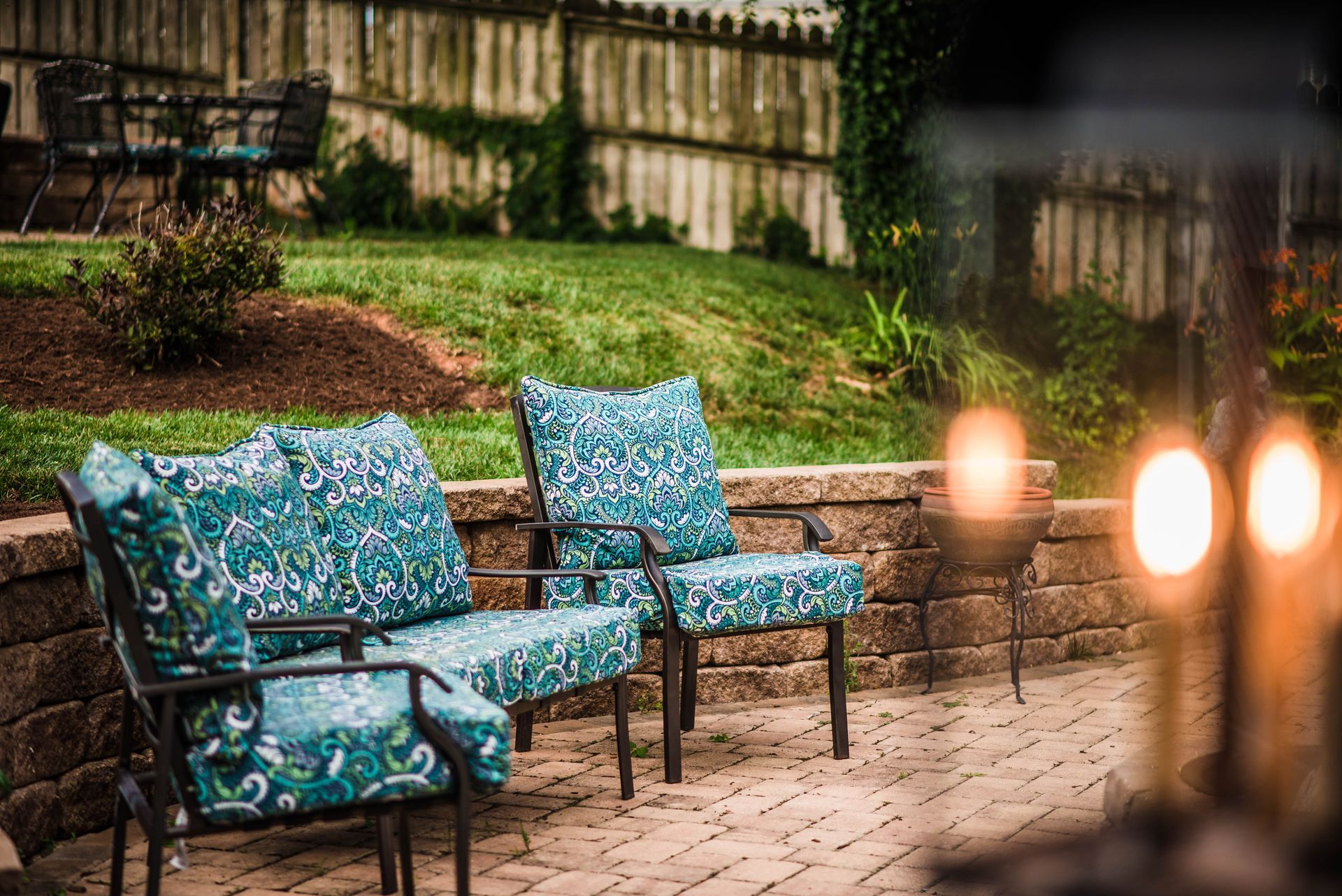 A patio with a couch and chairs and a fire pit.