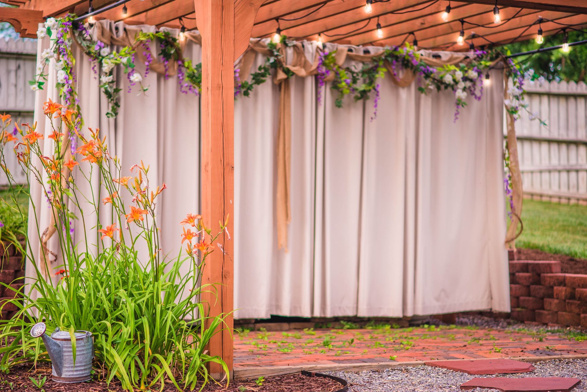 A wooden pergola with flowers and lights hanging from it.