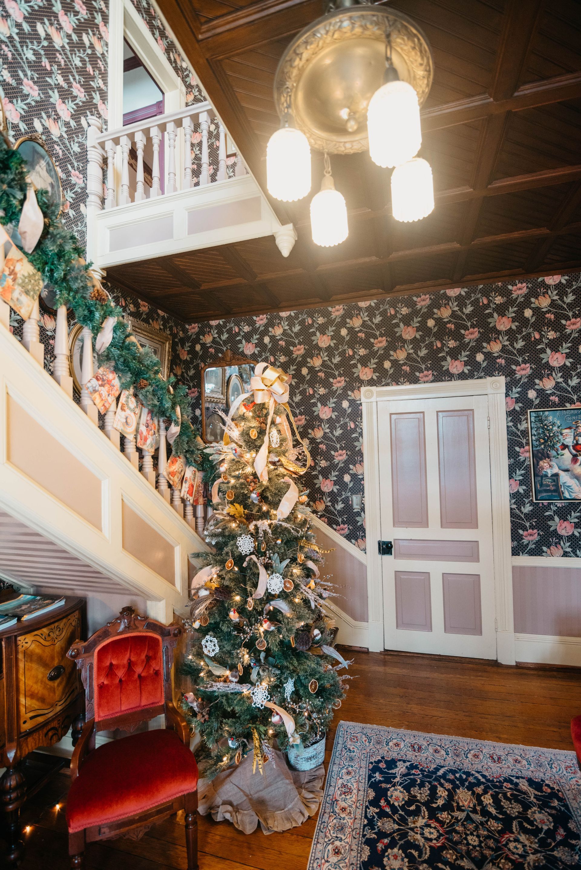 A christmas tree is sitting in a living room next to a staircase.