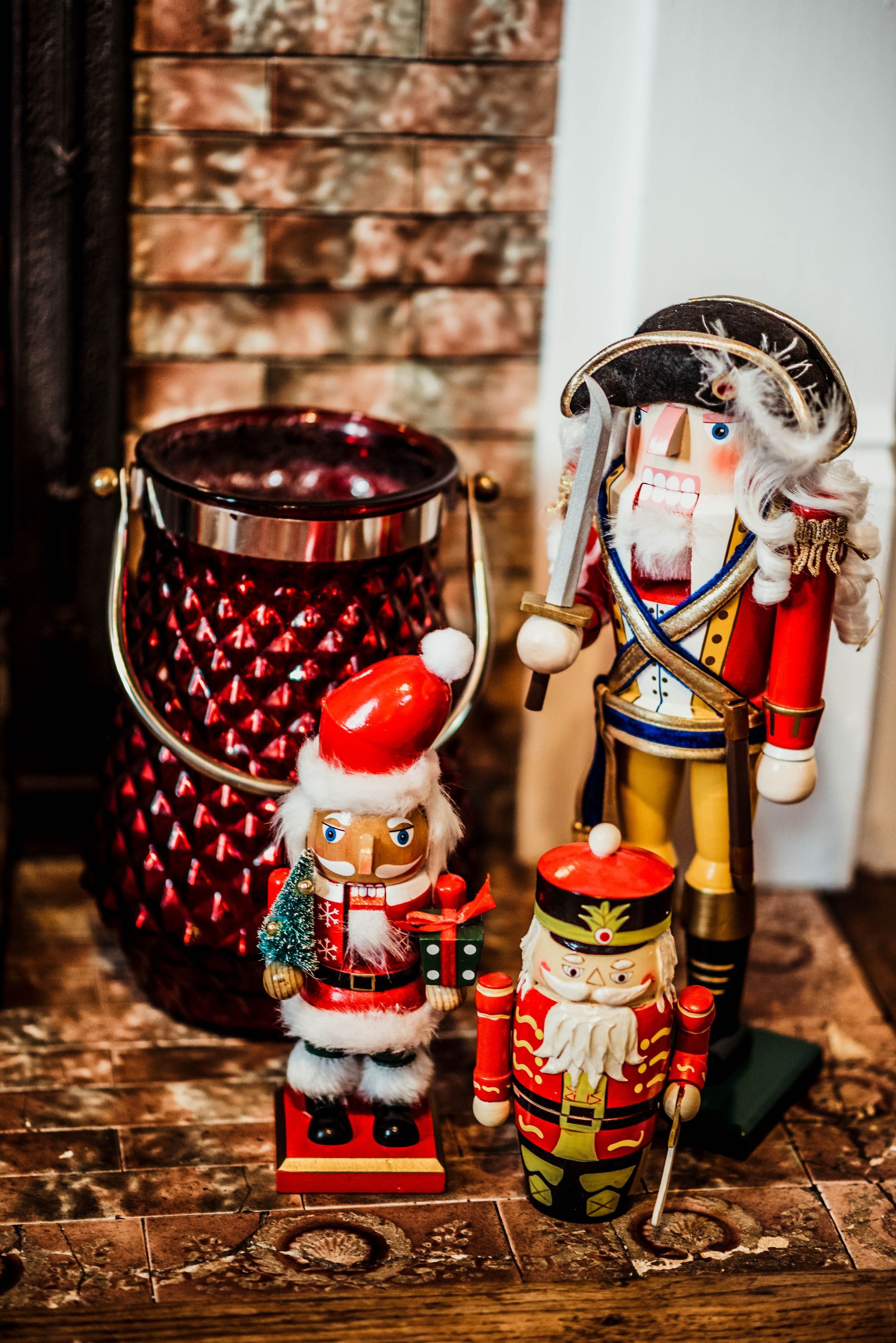 Three nutcrackers are sitting on a table next to a candle holder.