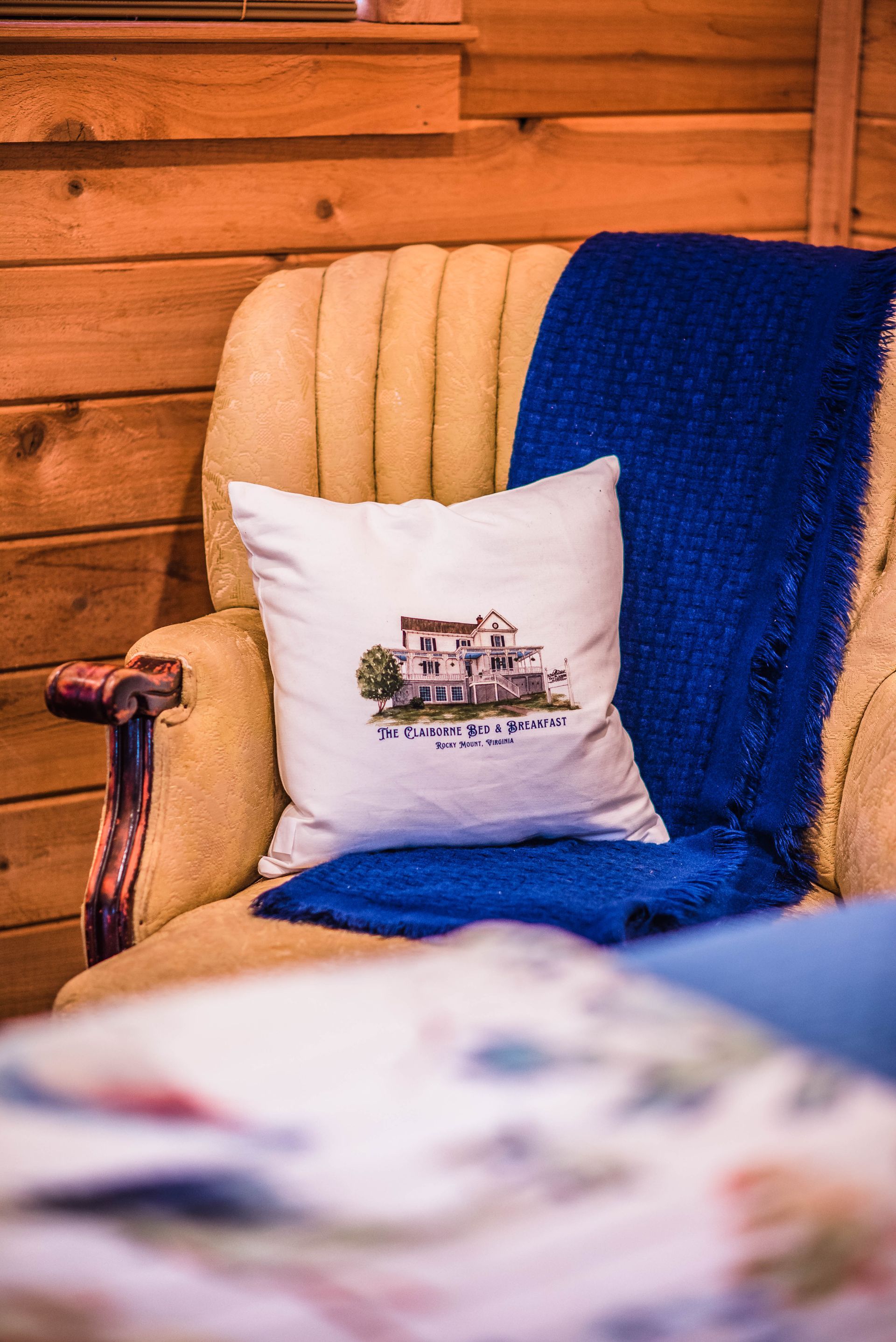 A chair with a pillow and a blue blanket on it.