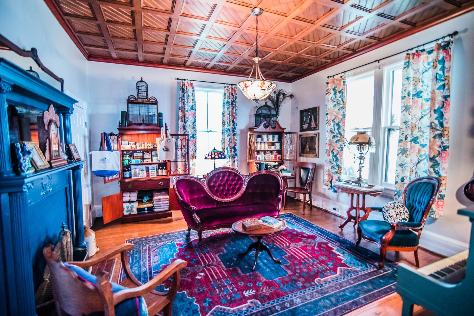 A living room with a purple couch , chairs , a piano and a rug.