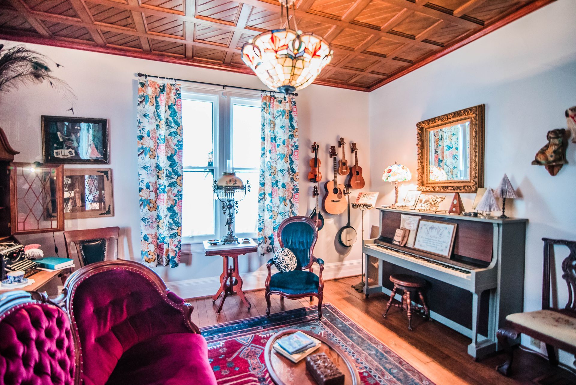A living room with a couch , chair , piano and guitars.