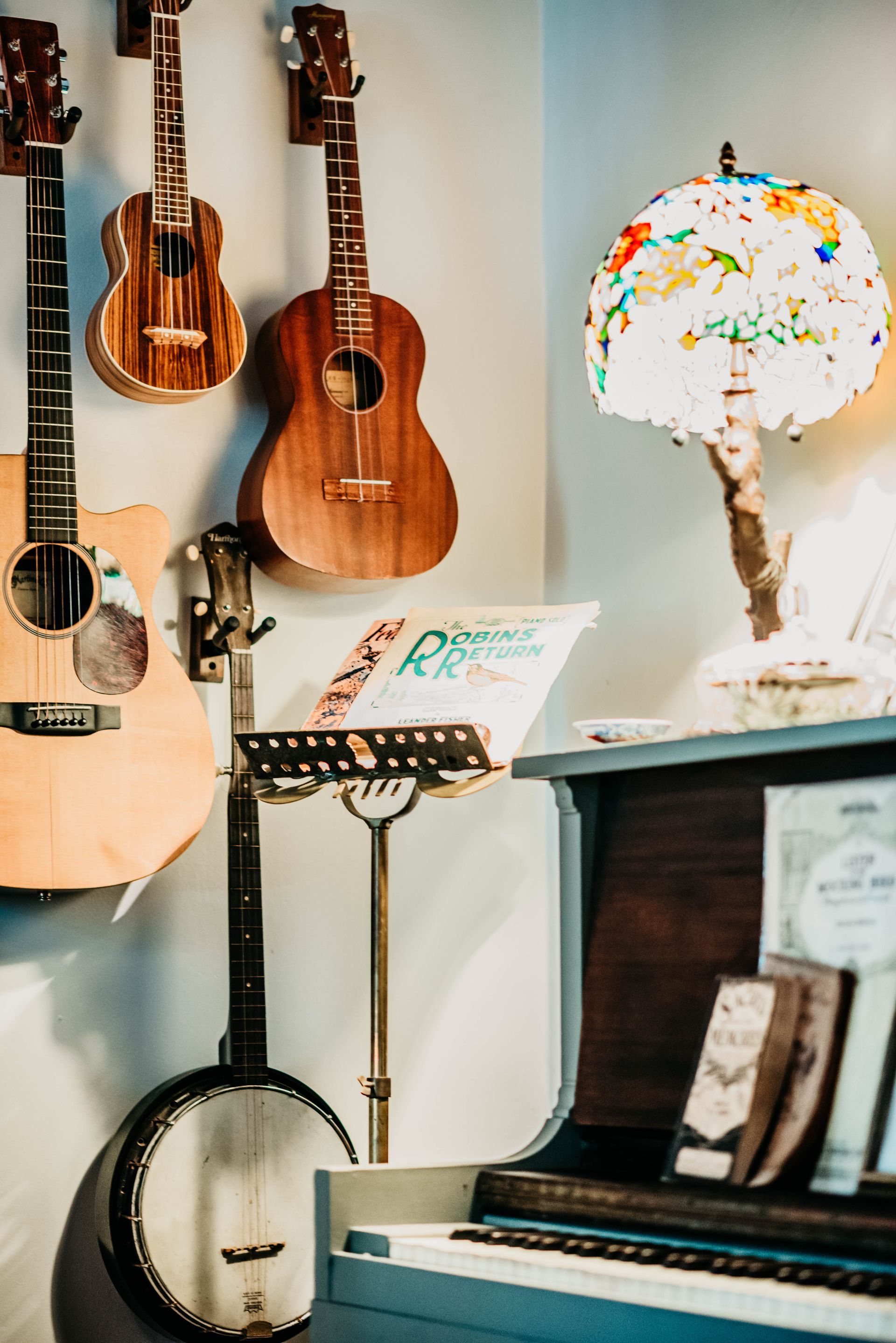 A bunch of guitars hanging on a wall next to a piano.