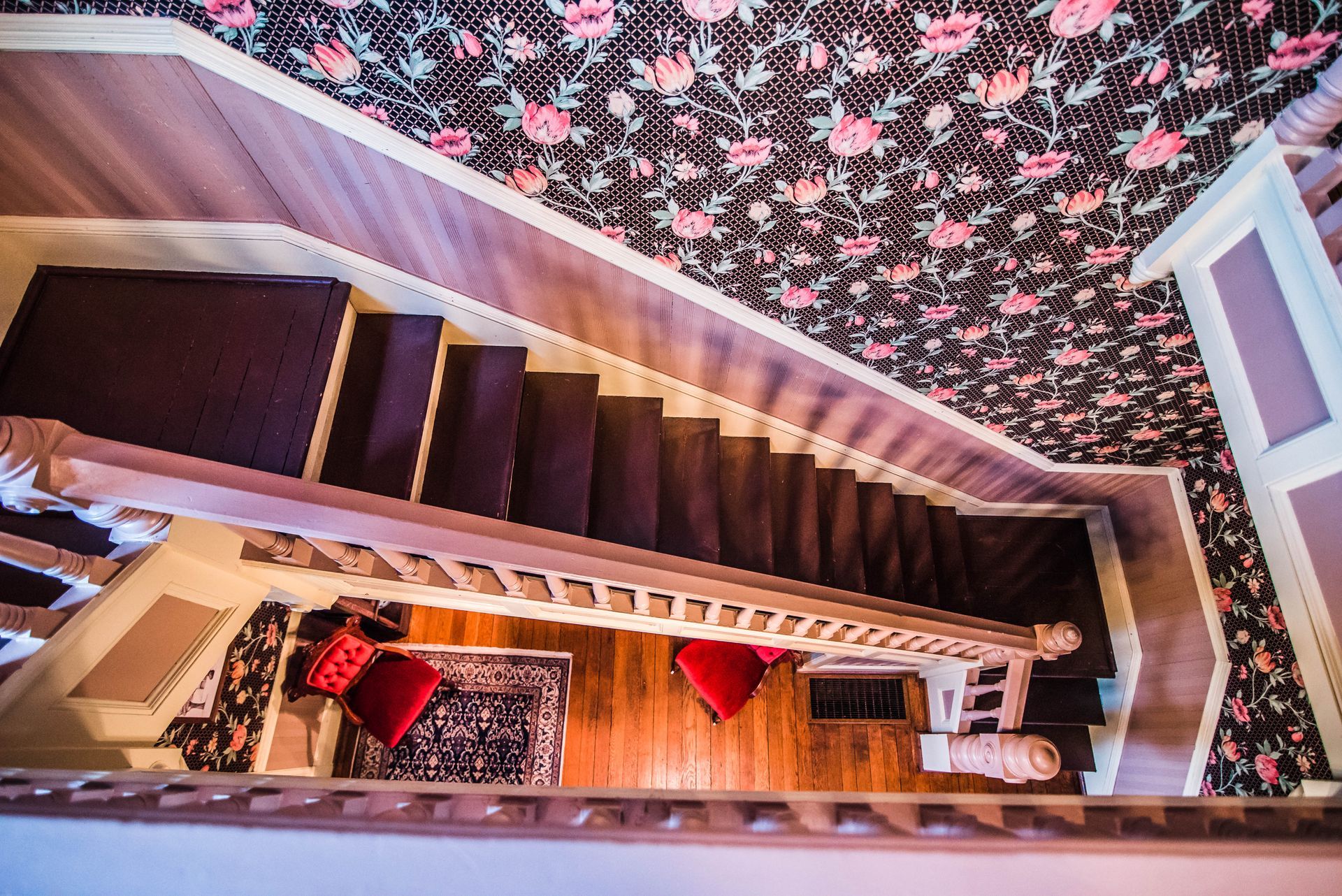 An aerial view of a staircase with a floral wallpaper on the wall.