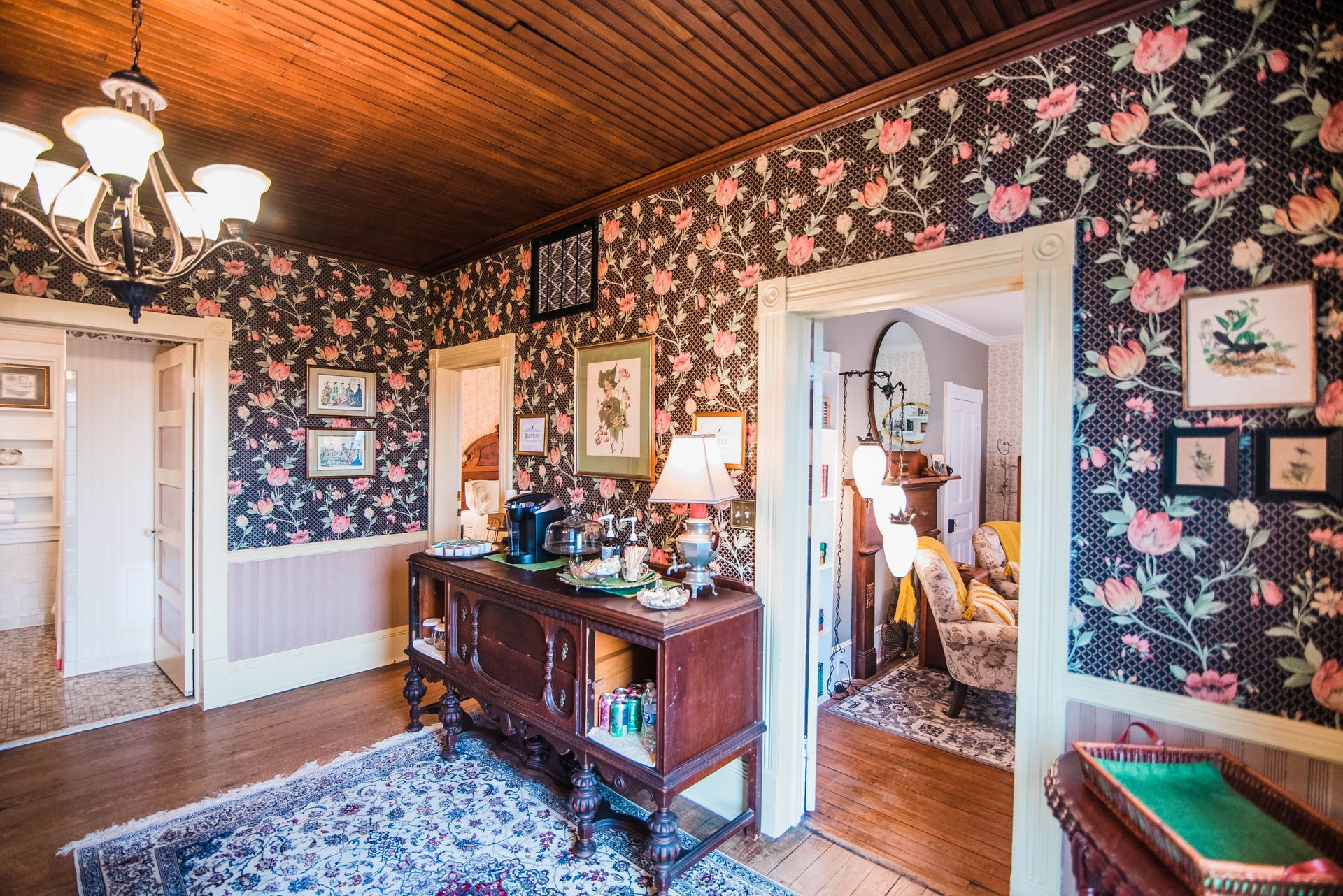 A living room with a floral wallpaper and a dresser.