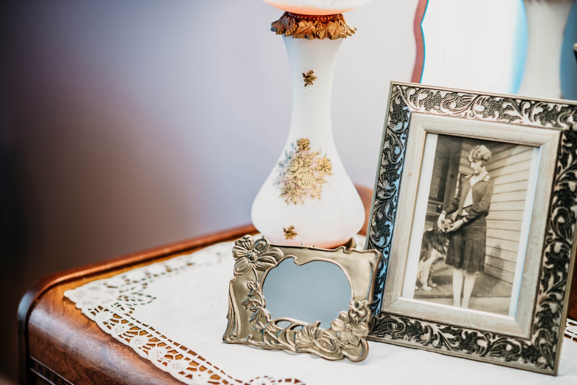 A lamp and two picture frames are on a table.