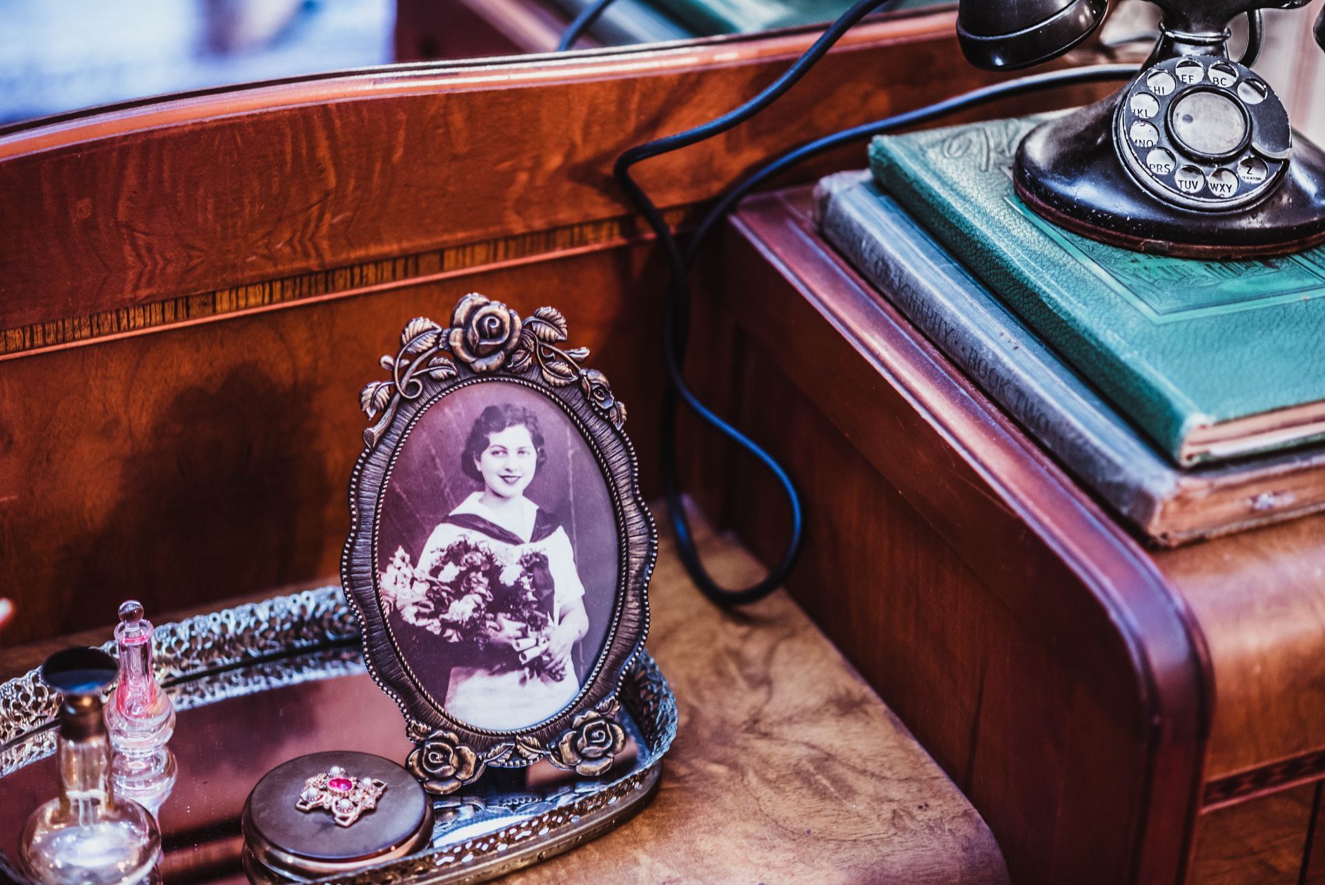 A picture of a woman in a frame is sitting on a table next to a telephone.