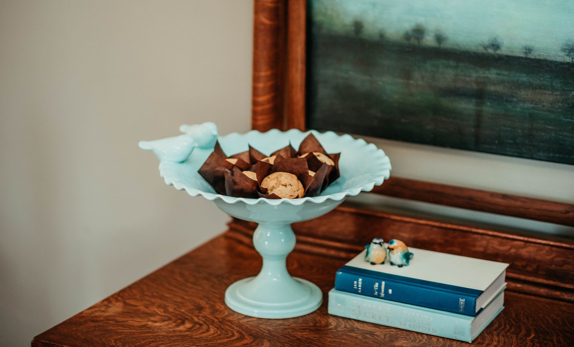 A bowl of cookies is sitting on a wooden table next to a stack of books.