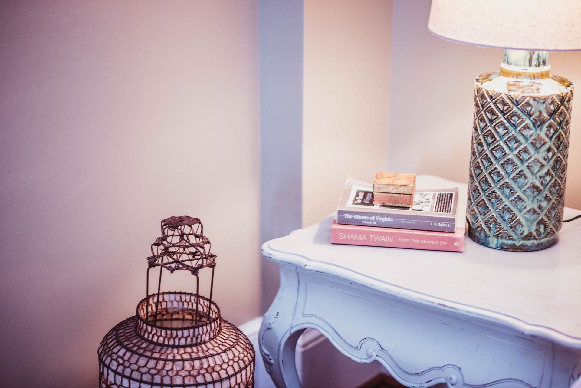 A lamp is sitting on a table next to a stack of books.