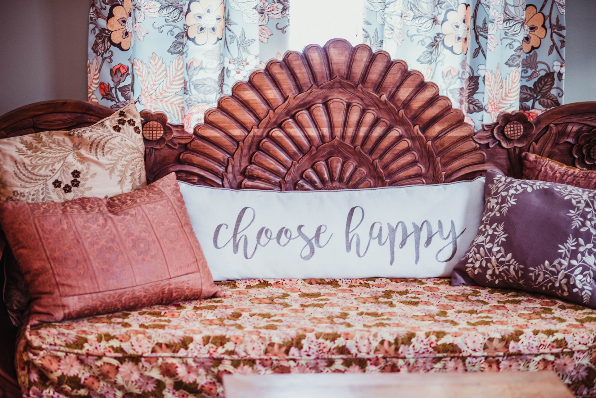 A bed with pillows and a sign that says `` choose happy ''.