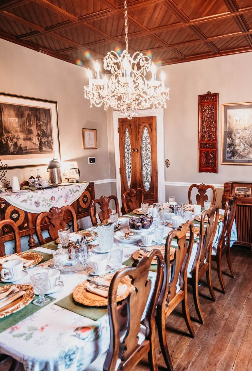 A dining room with a long table and chairs and a chandelier.