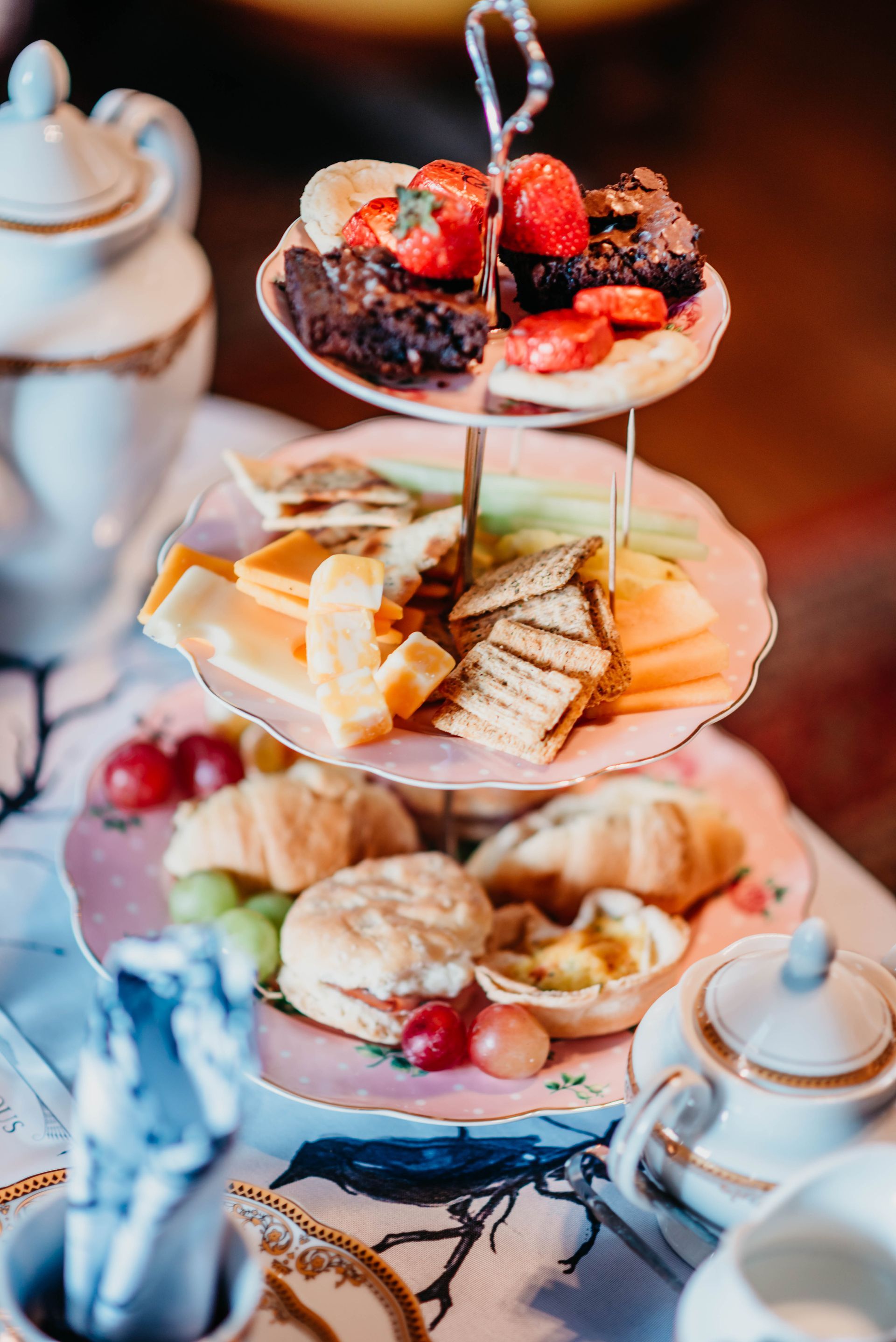 A three tiered cake stand filled with a variety of desserts on a table.