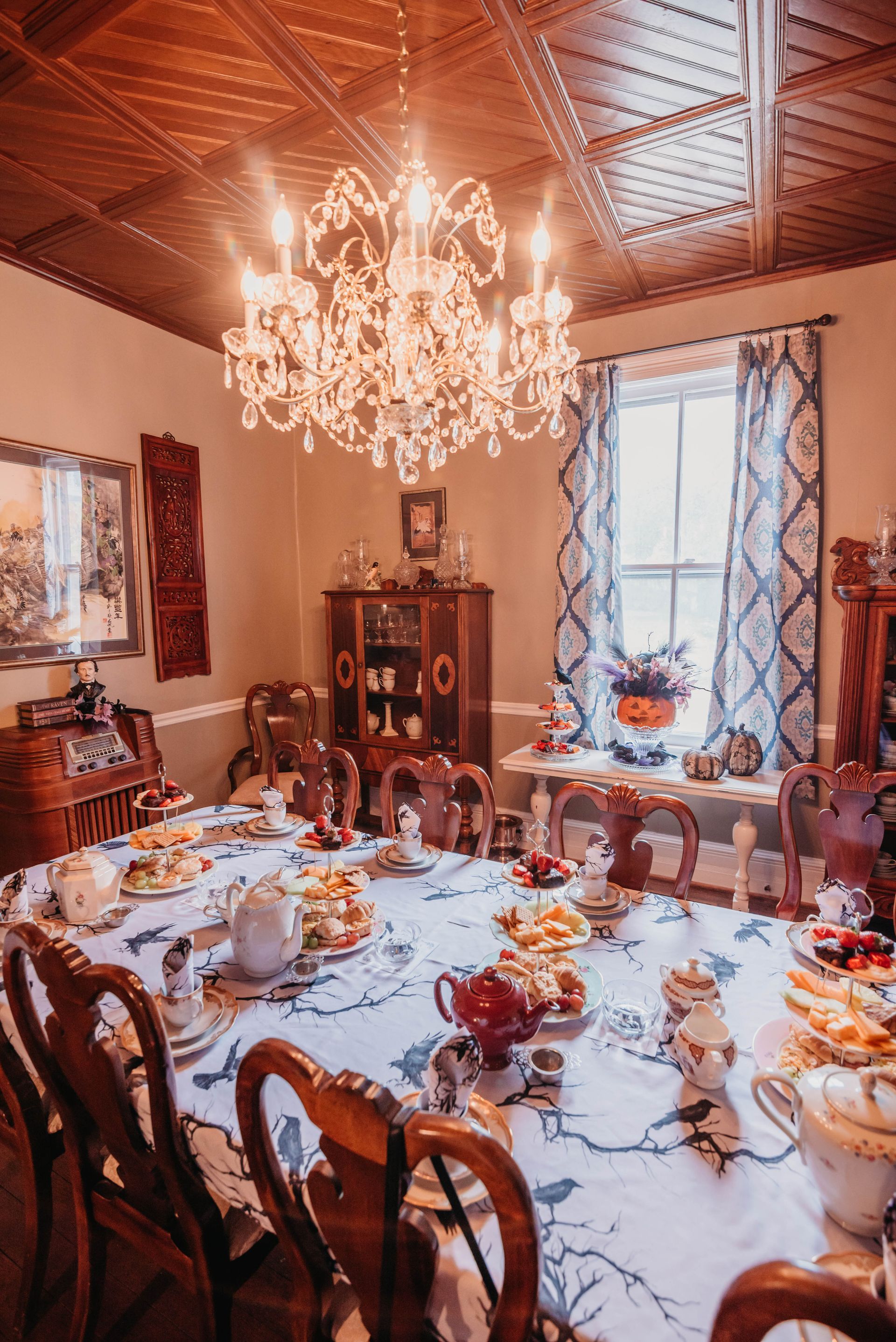 A dining room with a long table and chairs and a chandelier.