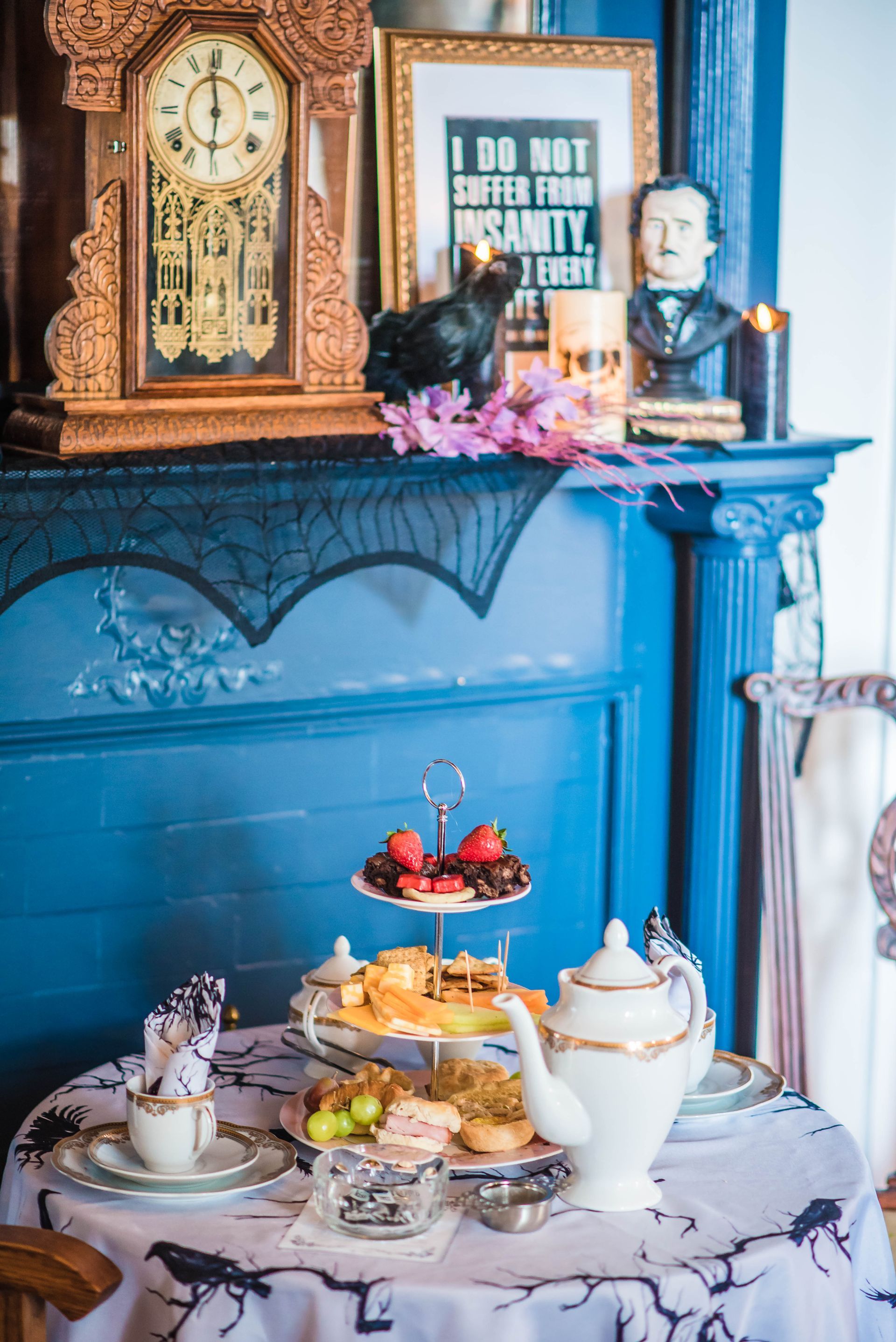 A table set for a tea party with a clock on the mantle.
