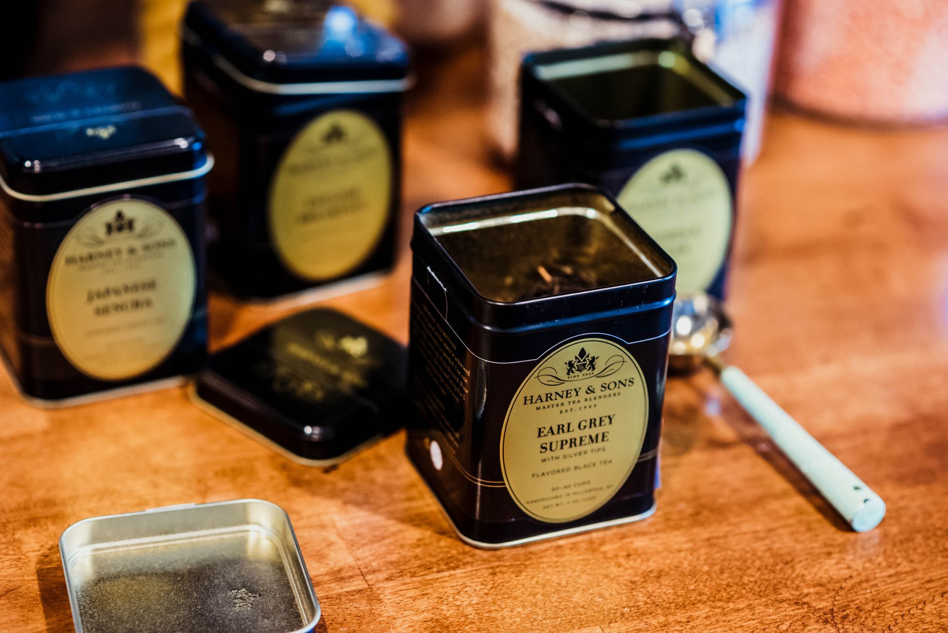 Four tins of tea are sitting on a wooden table.