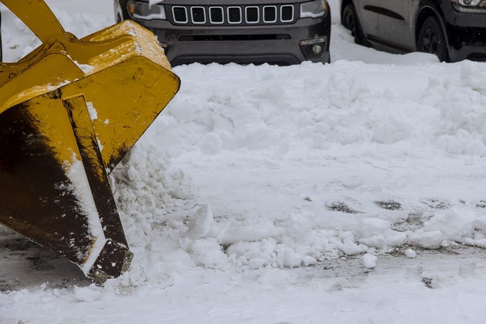 Un chasse-neige jaune déblaye la neige d'un parking.