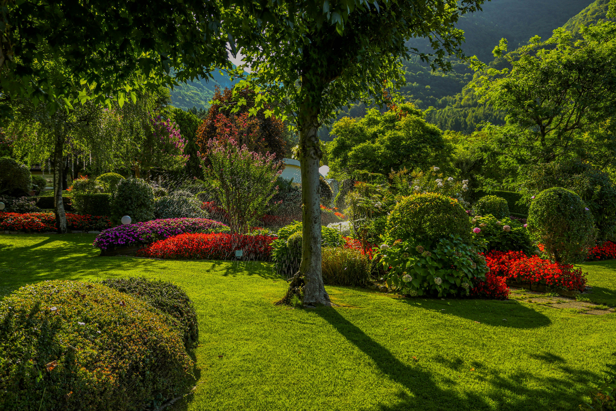 Lawn with a brick border separating green grass from a garden bed with flowers and mulch.