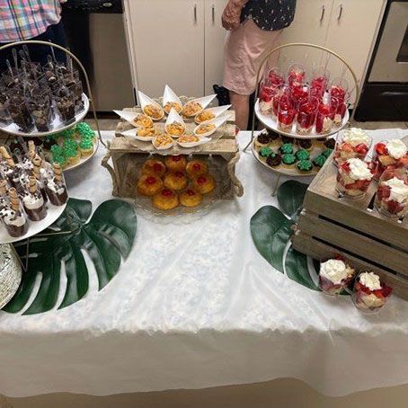 Woman in straw hat smiles, holding wine glass near a lake.