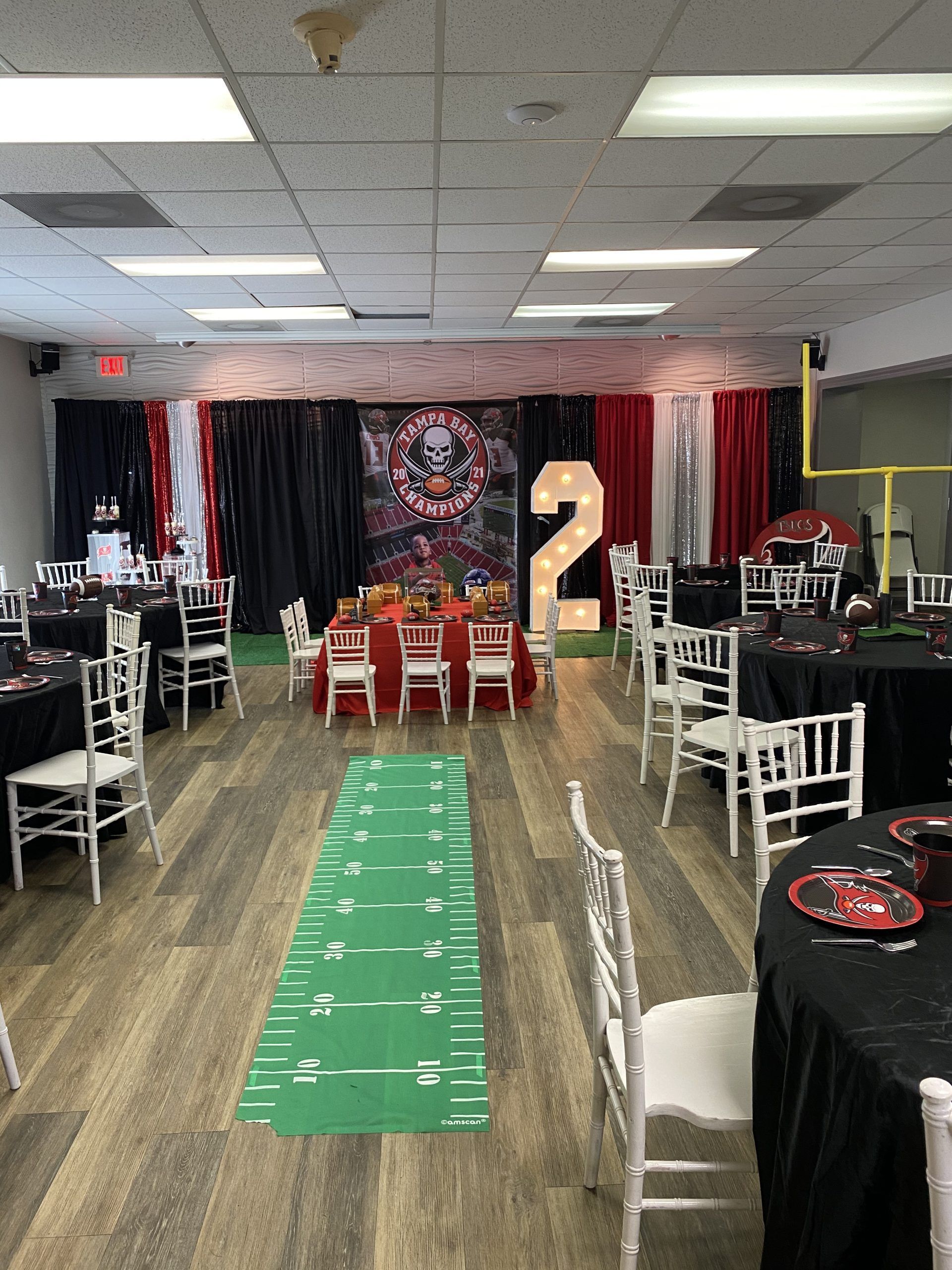 Woman in straw hat smiles, holding wine glass near a lake.