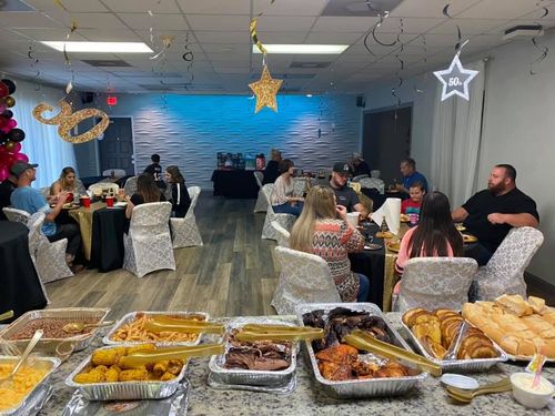 Buffet with food in front; party with guests seated at tables, some decorations.