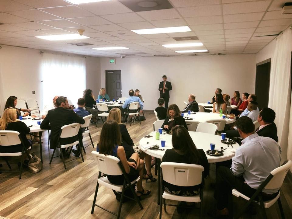 Woman in straw hat smiles, holding wine glass near a lake.