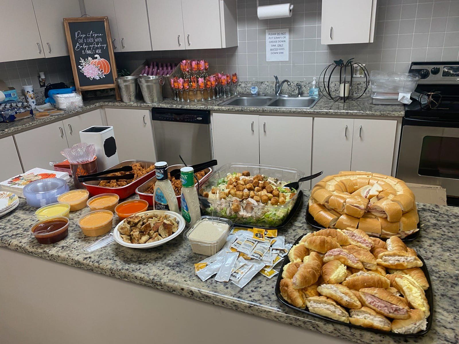 Woman in straw hat smiles, holding wine glass near a lake.