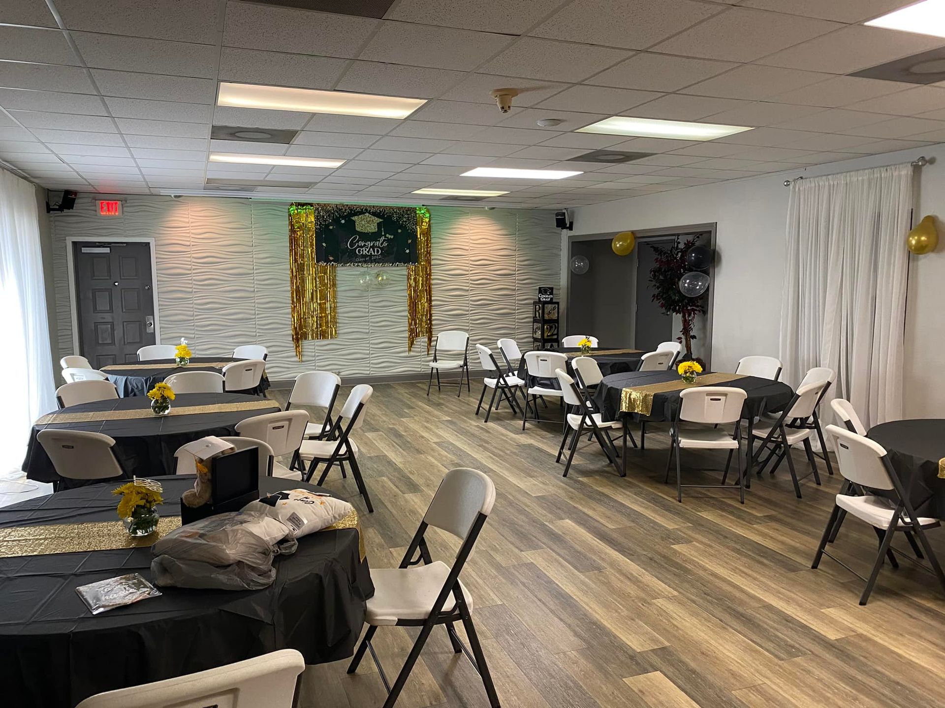 Woman in straw hat smiles, holding wine glass near a lake.