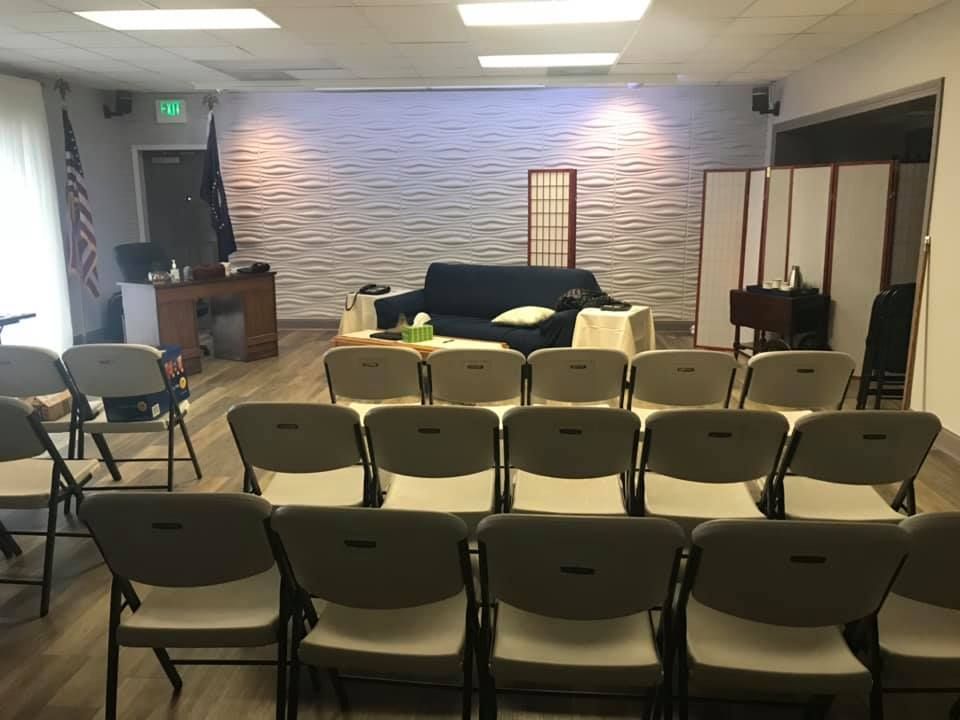 Woman in straw hat smiles, holding wine glass near a lake.