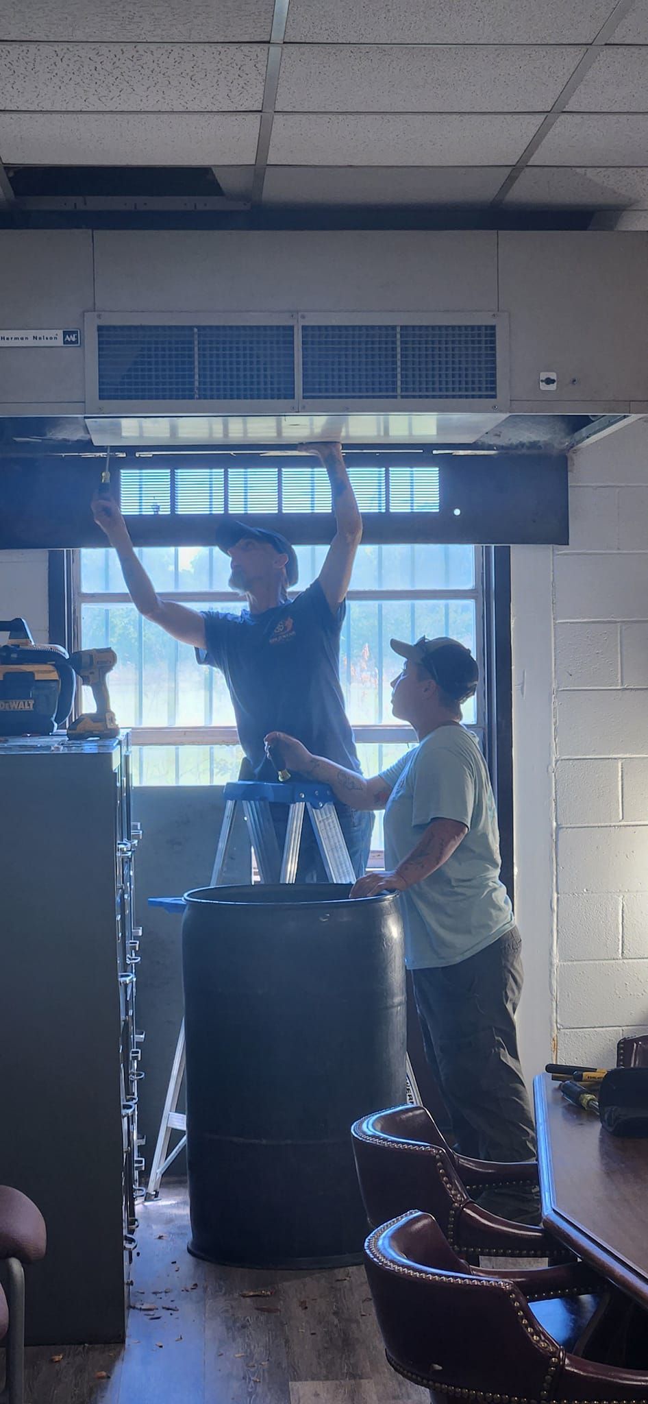 A man and a woman are working on a window in a room.