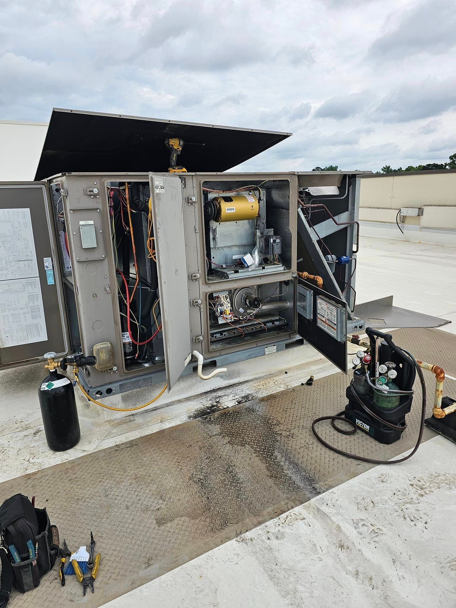 An air conditioner is being repaired on the roof of a building.