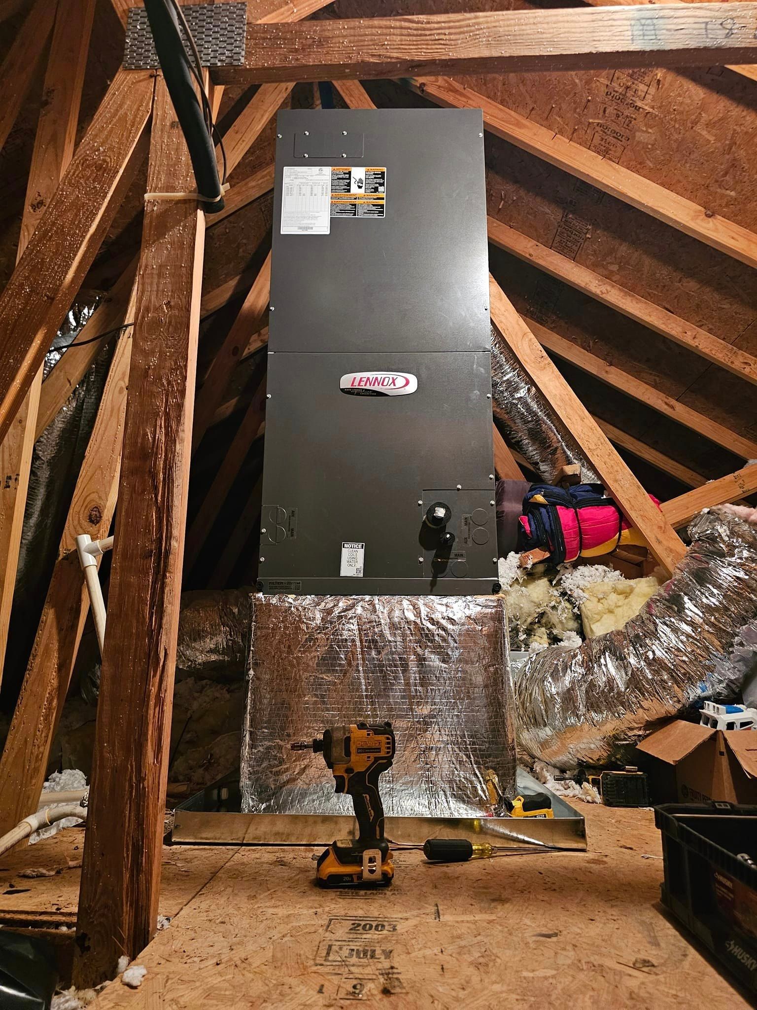 An air conditioner is being installed in an attic with a drill.