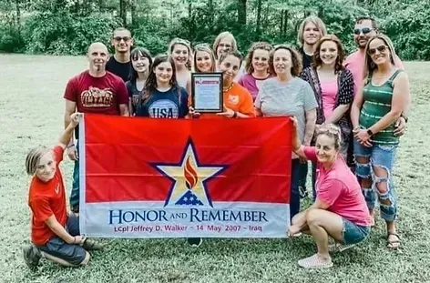 A group of people holding a flag that says honor and remember