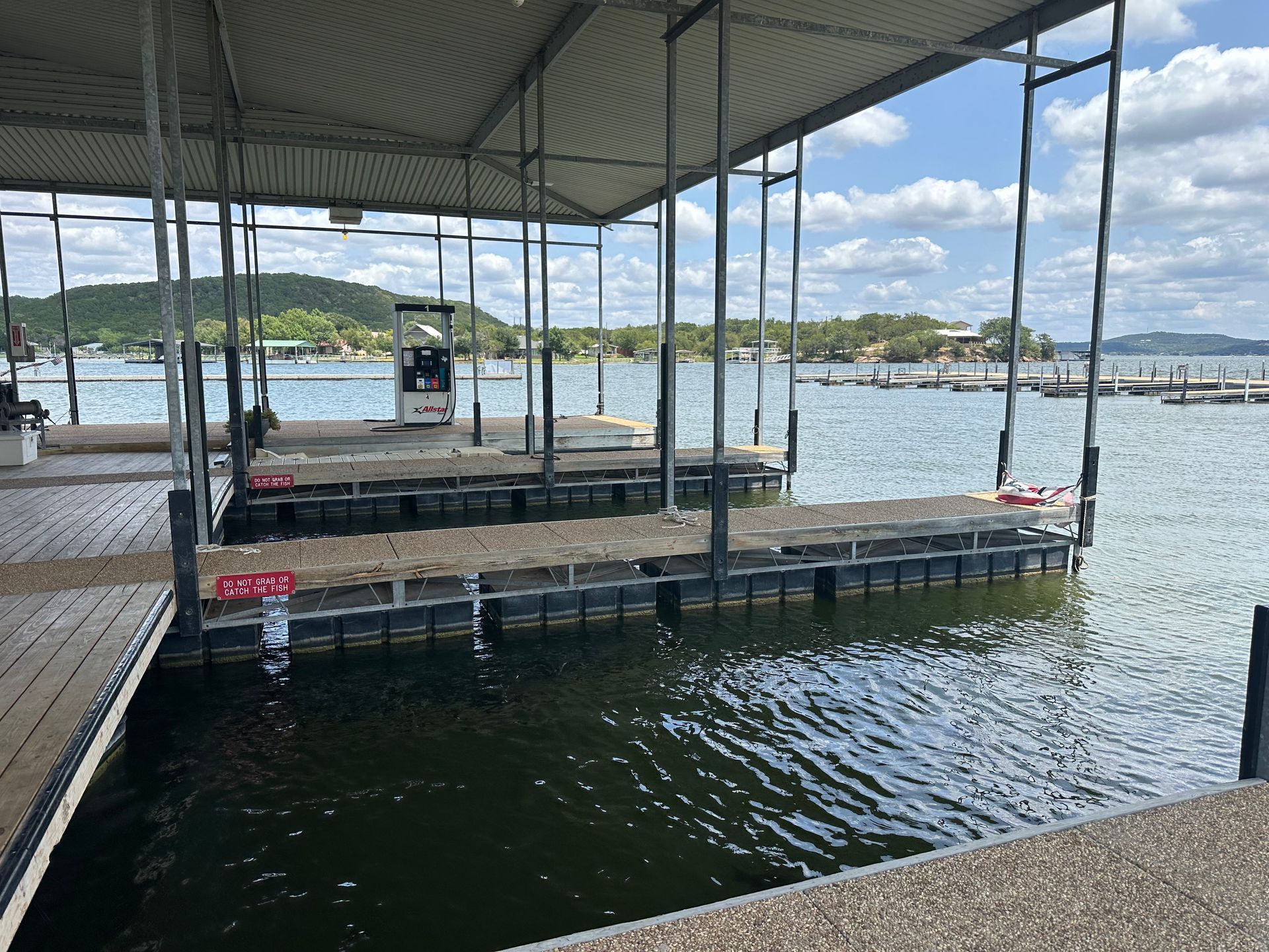A dock with a gas pump in the middle of the water.